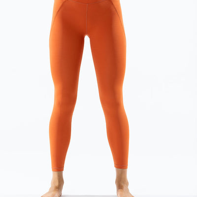 Front view of sunset orange Venatrix Eva leggings with sleek fit, high waistband, and functional side pockets.