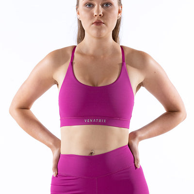 Front view of a pink ladies' sports bra in a bralette style, featuring wide straps and a smooth, supportive design for activewear.